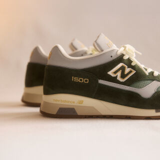 A pair of New Balance Made in UK sneakers on a green textured studio environment. 
