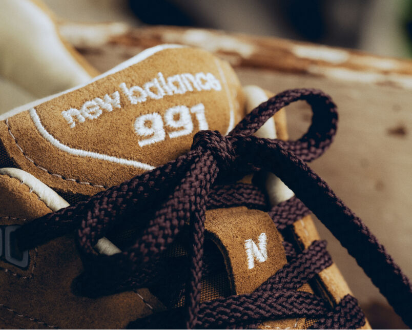 A pair of New Balance Made in UK sneakers sitting in a white studio environment. 