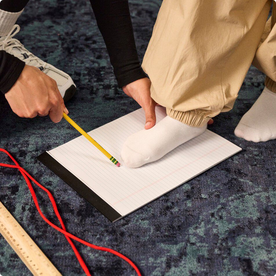 Woman tracing around child's foot with a pencil