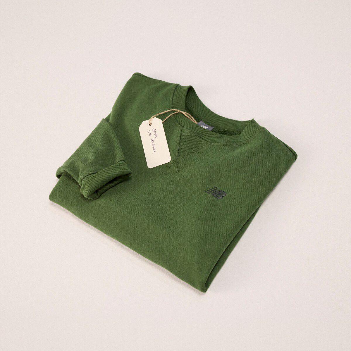 Green sweatshirt folded into a square on a grey background.