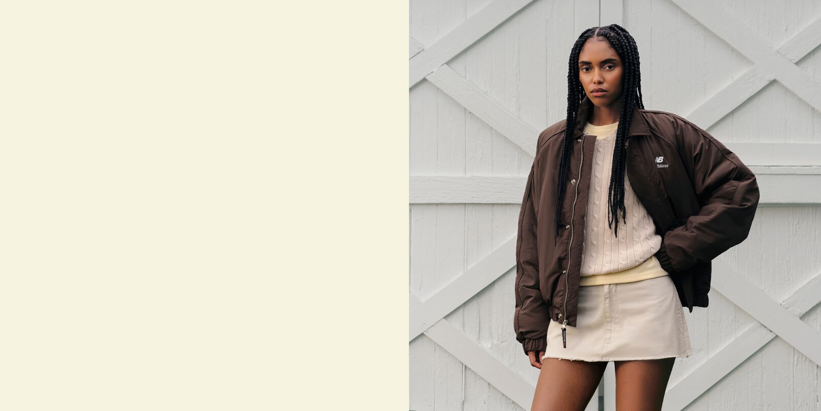 A woman standing in front of a barn wearing a New Balance jacket.